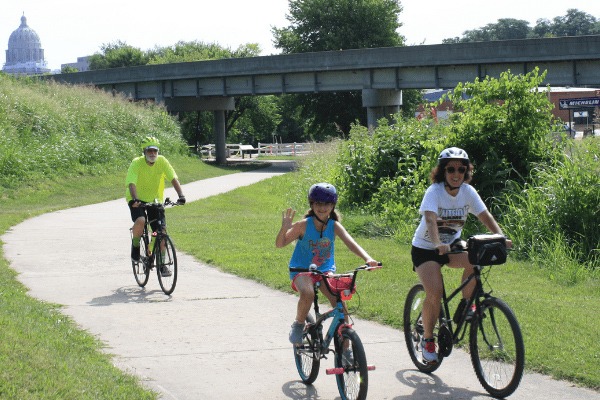 Family of three on a community bike ride with capitol building in background.