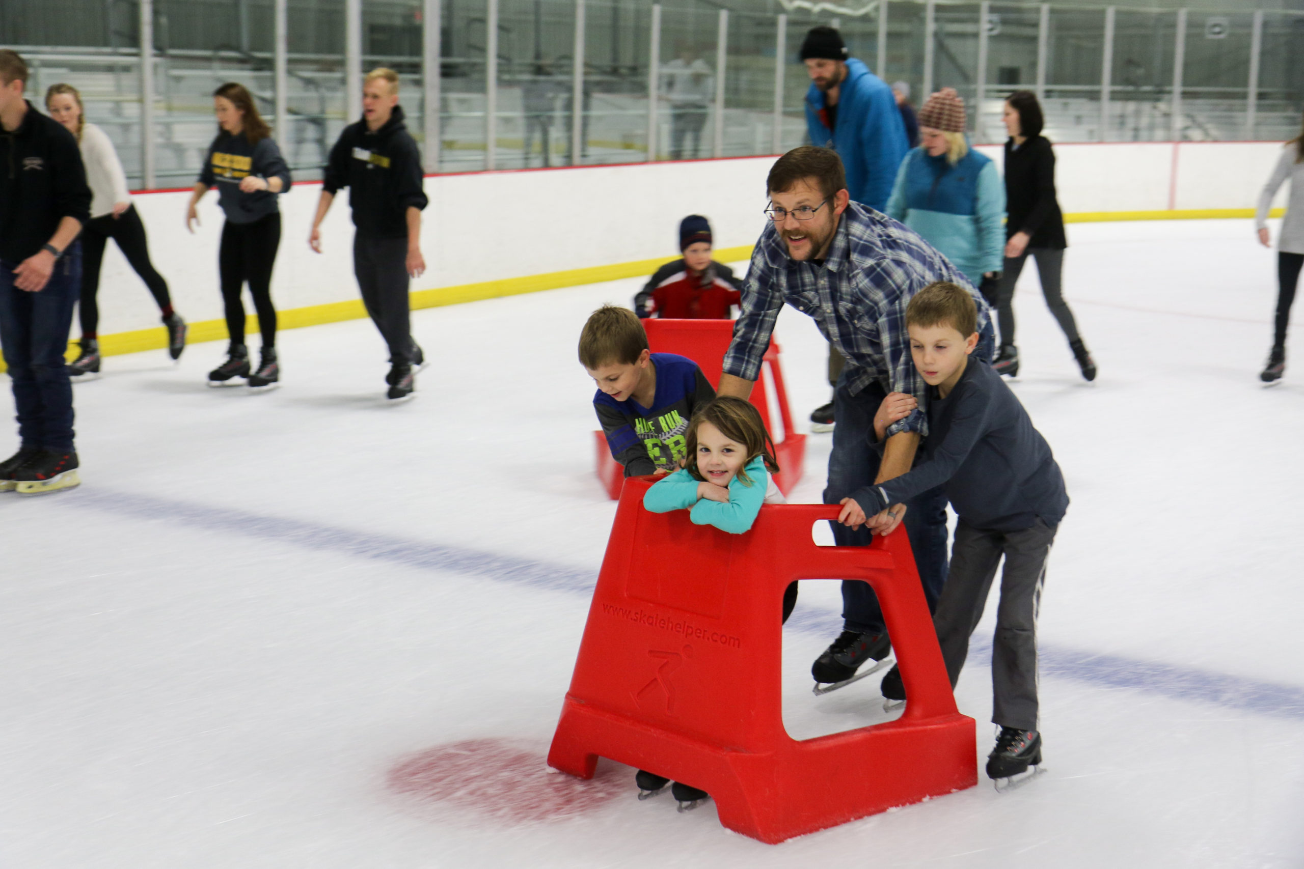 Father ice skating with his kids